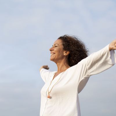 Mujer madura feliz con los brazos abiertos al cielo